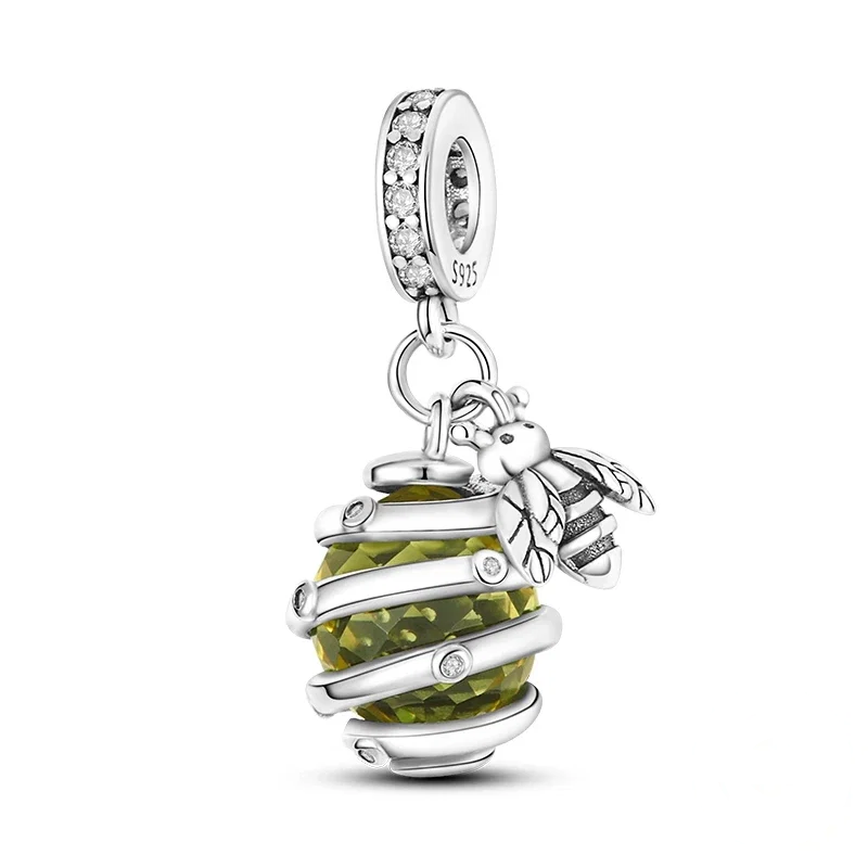 Charm de prata polida com uma abelha detalhada pousada sobre uma colmeia esférica, que contém um cristal facetado.