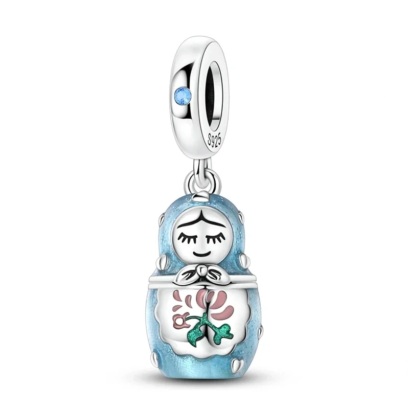Amuleto de boneca matrioska em prata com detalhes florais e esmalte azul claro, que se abre para revelar uma miniatura interna